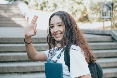 Young woman drinking water while standing against wall