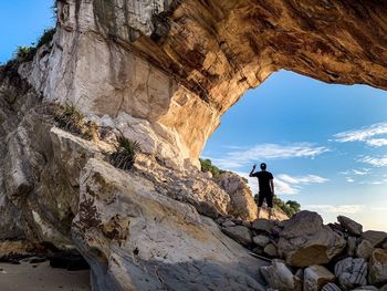 Man standing on rock against sky