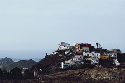 Cityscape by sea against clear sky