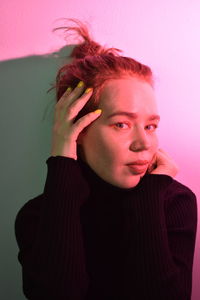 Portrait of beautiful young woman against pink background