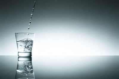 Close-up of glass over water against white background