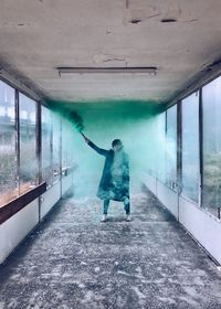 Woman with green smoke flare in corridor