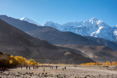 People standing against snowcapped mountain during sunny day