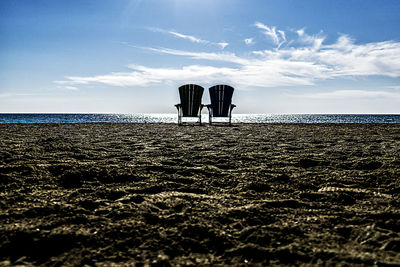 Chairs on shore at beach against sky