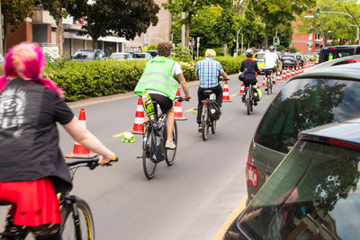 Rear view of people riding bicycle on road