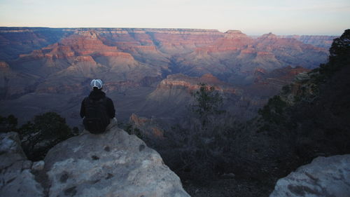 Rear view of people sitting on rock