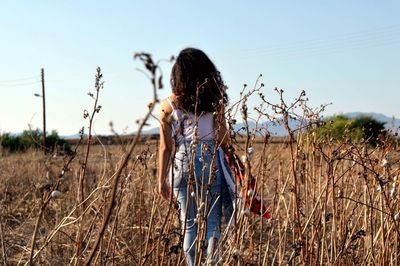 Rear view of woman on field against clear sky