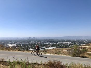 Man riding bicycle on mountain against sky