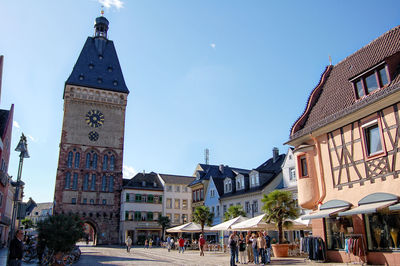 People in front of clock tower against blue sky