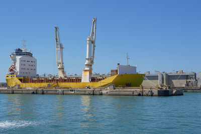 Buildings by sea against clear sky