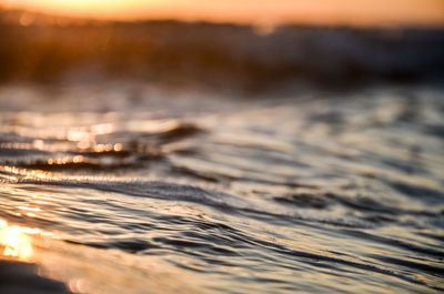 Surface level of beach against sky during sunset