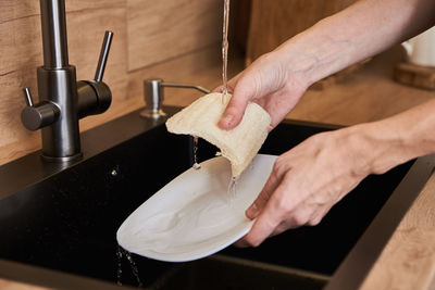 Woman washes dishes with organic eco friendly sponge. zero waste concept