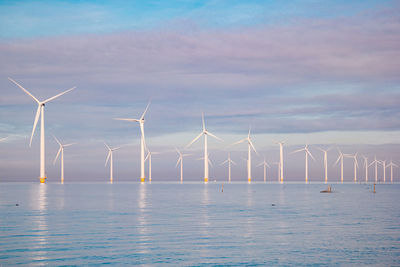 Wind turbines in sea against sky