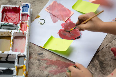 Low section of child painting heart shape on floor