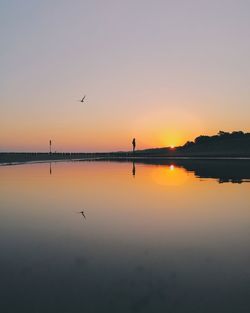 Scenic view of lake against clear sky during sunset