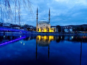 Reflection of mosque in lake against cloudy sky at dusk