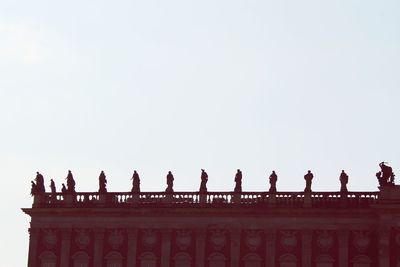 Low angle view of birds perching on roof against sky