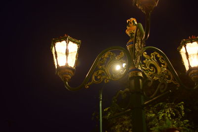 Low angle view of illuminated light bulb against sky at night