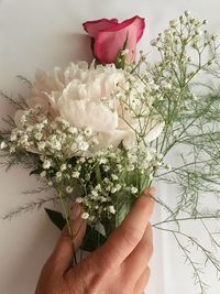 Cropped hand holding bunch of flowers on table