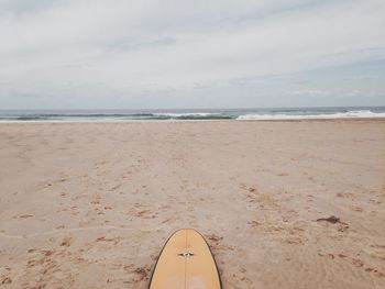 Surfboard on beach against sky