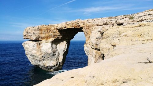 Rock formation by sea against sky