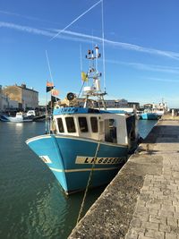 Ship moored at harbor against blue sky