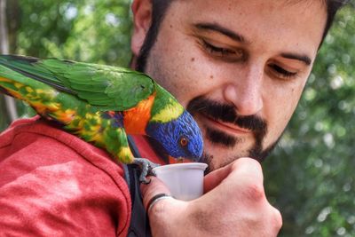 Portrait of man holding bird perching outdoors