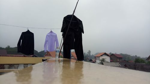 Clothes drying by buildings against sky during rainy season