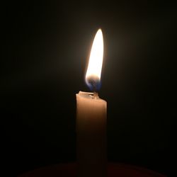 Close-up of illuminated candle against black background