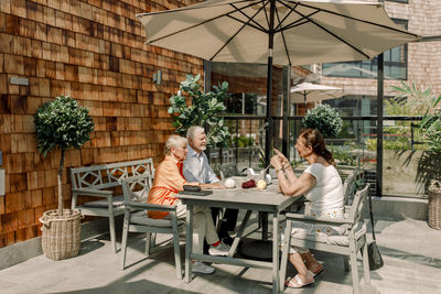 Senior man and women talking while sitting at dining table on sunny day