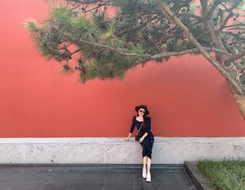 Full length portrait of woman standing against wall