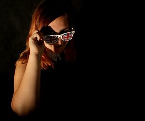 Portrait of woman wearing sunglasses against black background