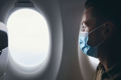 Portrait of man looking through airplane window