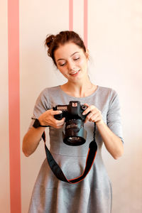 Portrait of a smiling young woman holding camera
