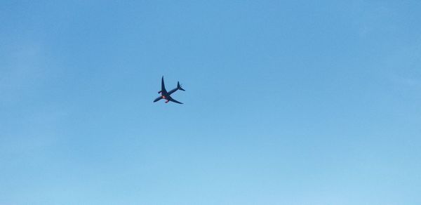 Low angle view of airplane against clear blue sky