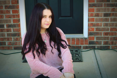 Portrait of young woman against brick wall