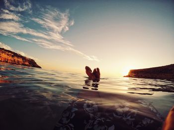 People sitting on shore against sky during sunset