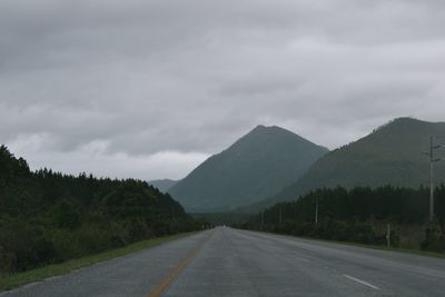 Road by mountains against storm clouds