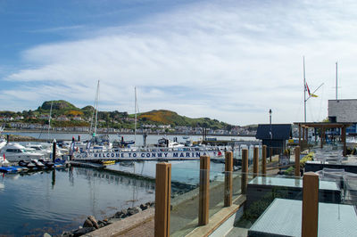 Sailboats moored at harbor against sky