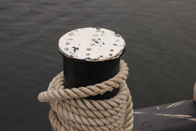 Close-up of rope on bollard against sea