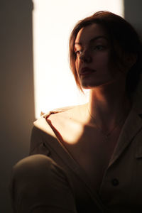 Thoughtful young woman looking away while sitting at home