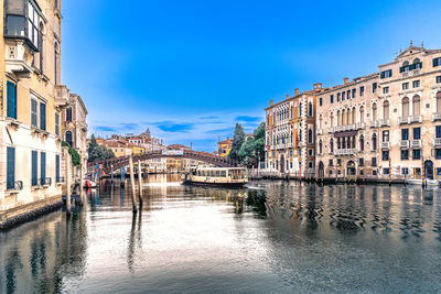 Canal amidst buildings against clear blue sky