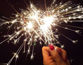 Cropped image of woman hand holding sparkler at night