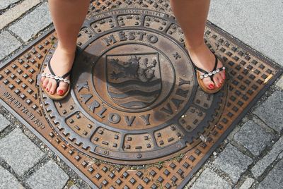 Low section of woman standing on manhole