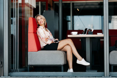 A beautiful girl is sitting at a table in a cafe and thoughtfully looks into the distance