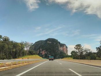 Road by trees against sky