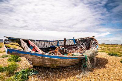 Fishing boats moored on field against sky