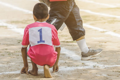 Low section of boy crouching on running track