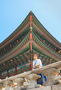 Low angle view of man sitting against building