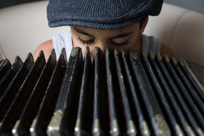 Close-up of playing accordion while sitting on seat at home